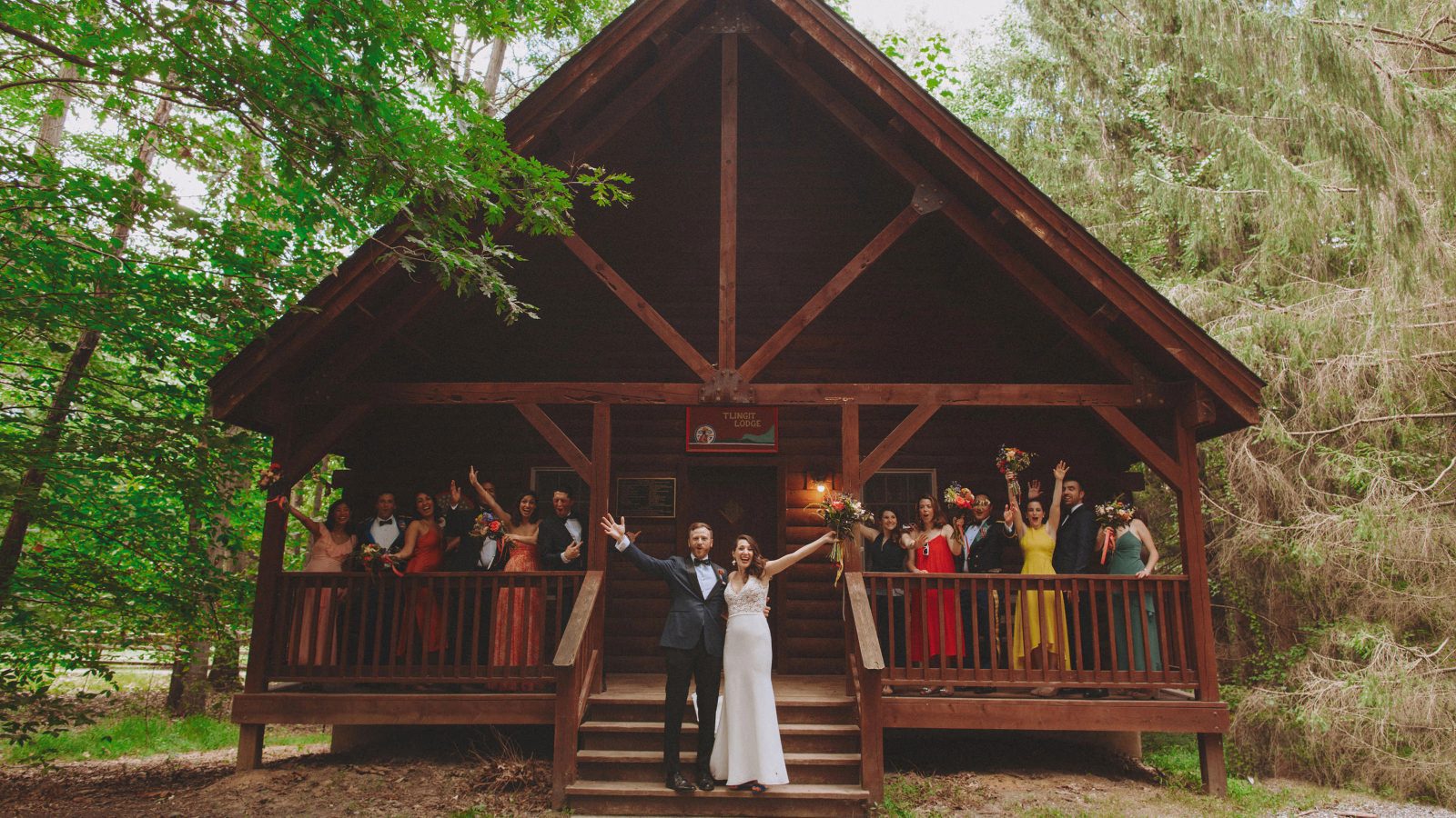 Bridal party in front of a log cabin