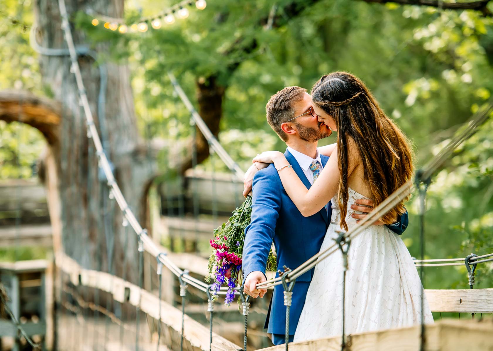Bride and groom embracing on rope bridge