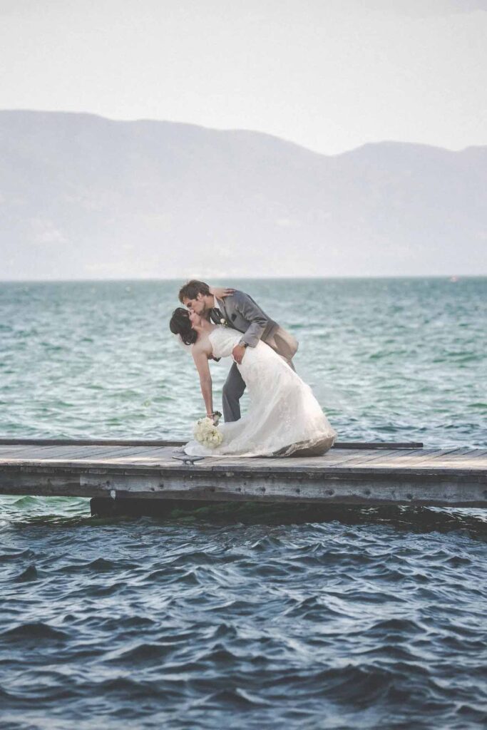 Bride and groom embracing on lake dock