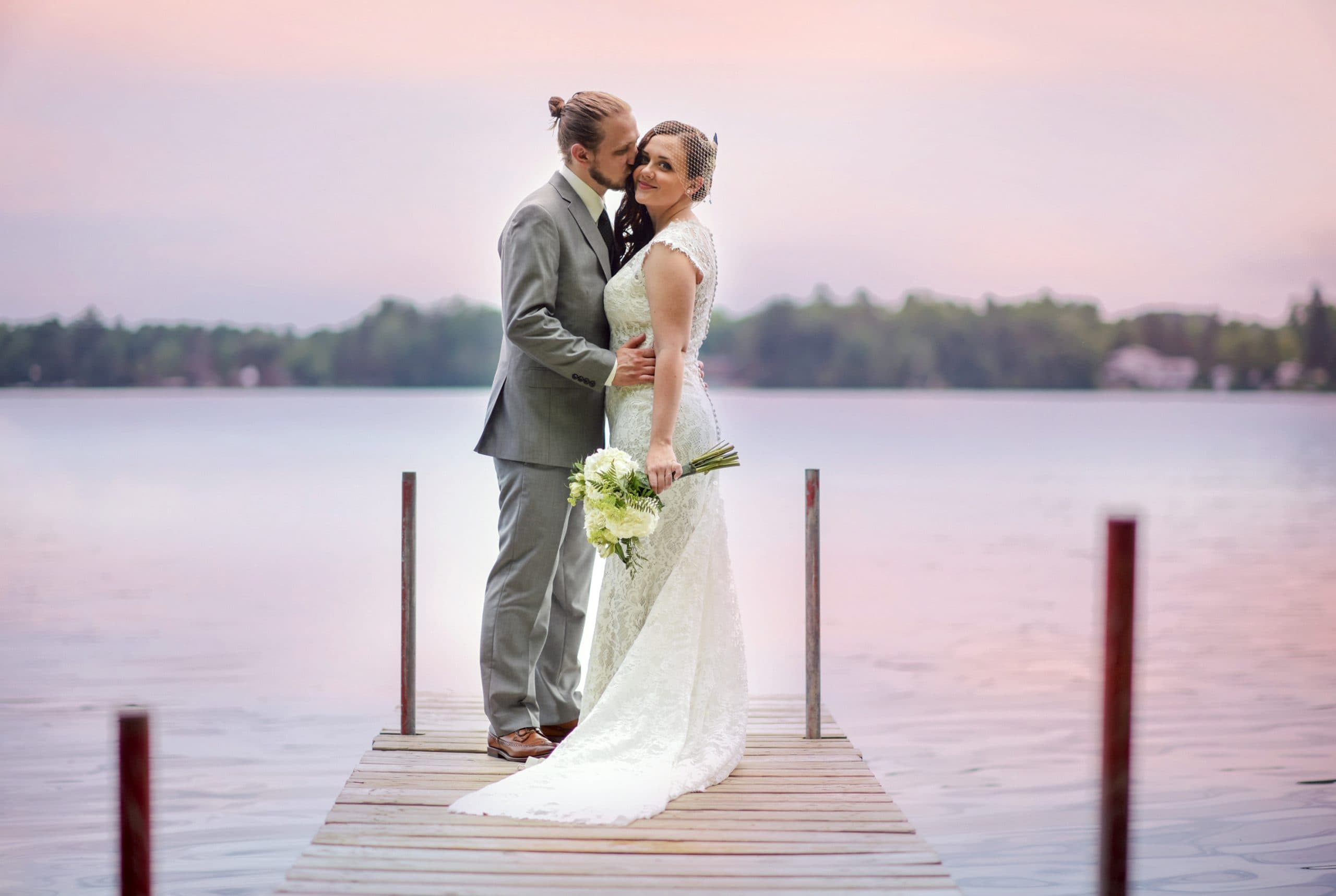 Bride and groom embracing on camp dock