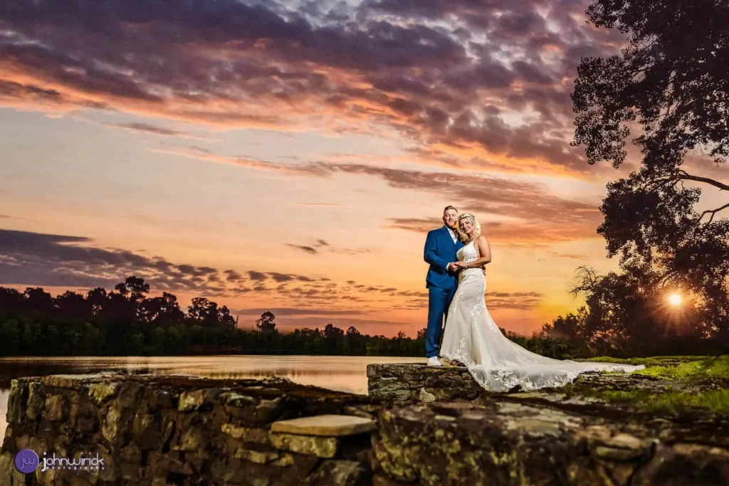 Bride and groom near lake during sunset