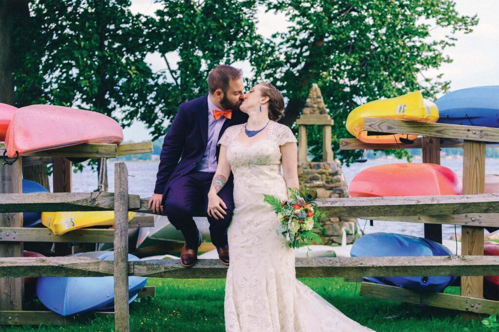 Bride and groom embracing near kayaks